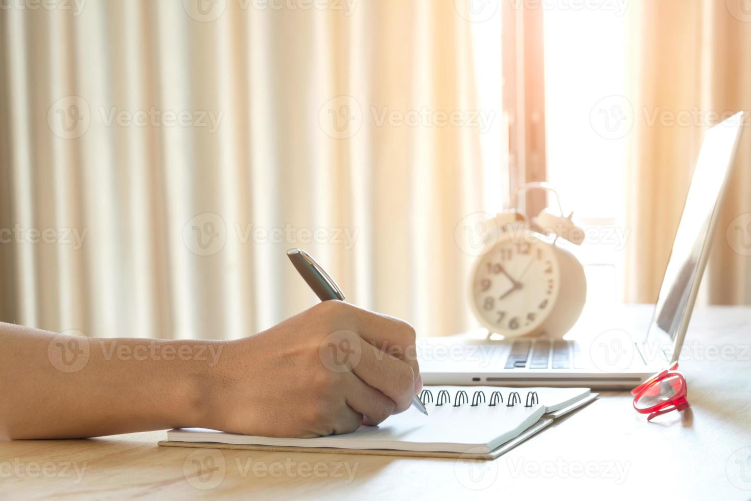mão humana escrevendo no caderno na mesa de trabalho foto