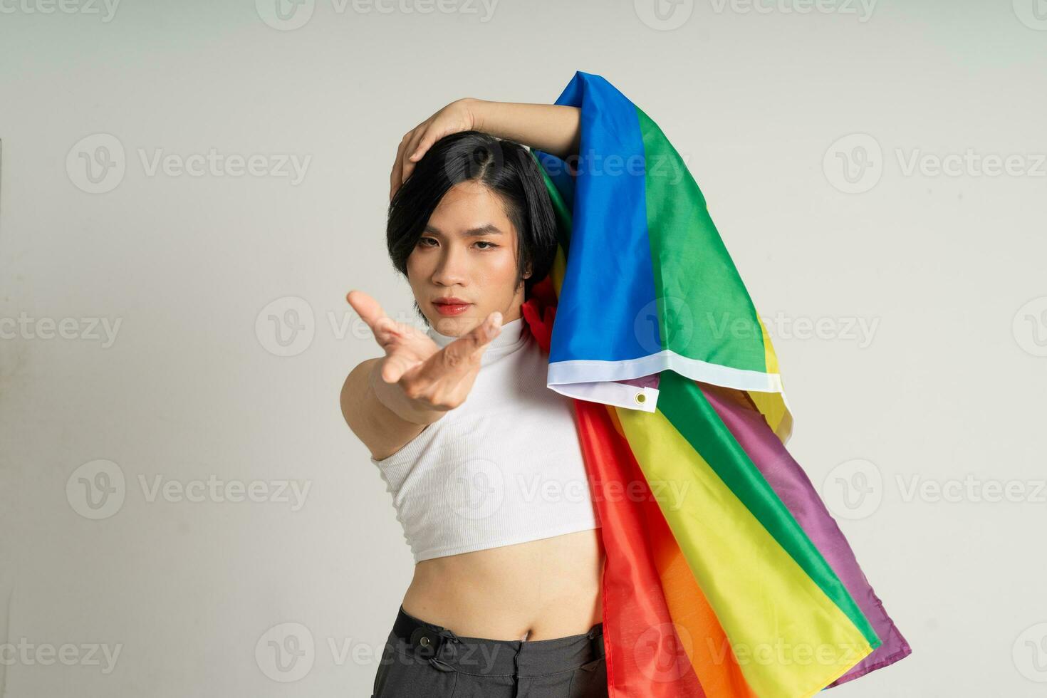 imagem do ásia gay homem segurando uma arco Iris bandeira com confiança posando em uma branco fundo foto
