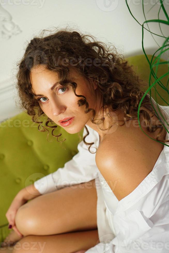 jovem feliz com cabelo encaracolado em uma camisa branca em casa foto