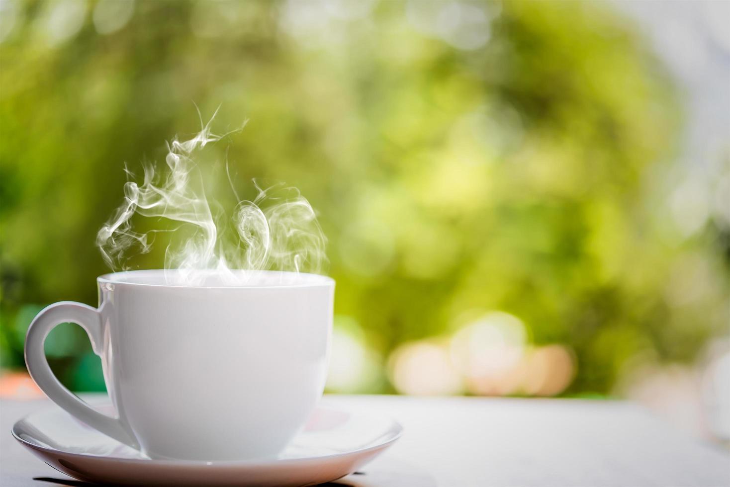 xícara de café branca em cima da mesa de madeira com fundo desfocado foto