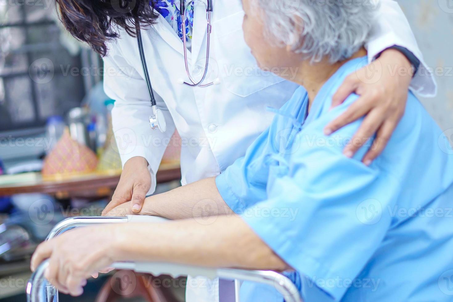 médico asiático toca e cuida de paciente idosa com andador foto