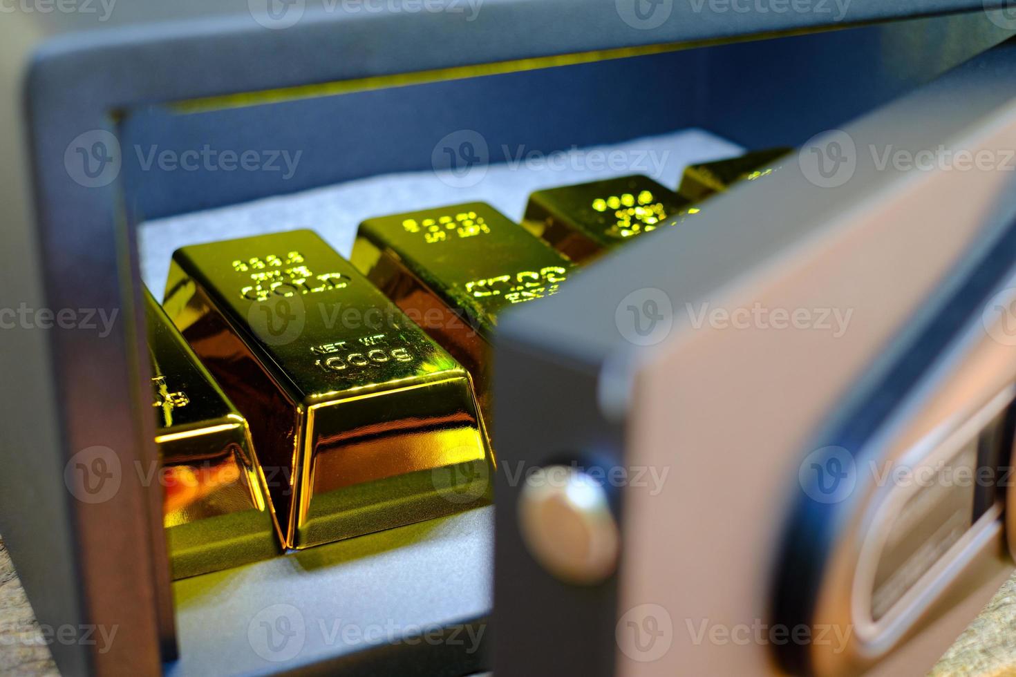 caixa de cofres de aço cheia de pilhas de moedas e barra de ouro na mesa de madeira foto