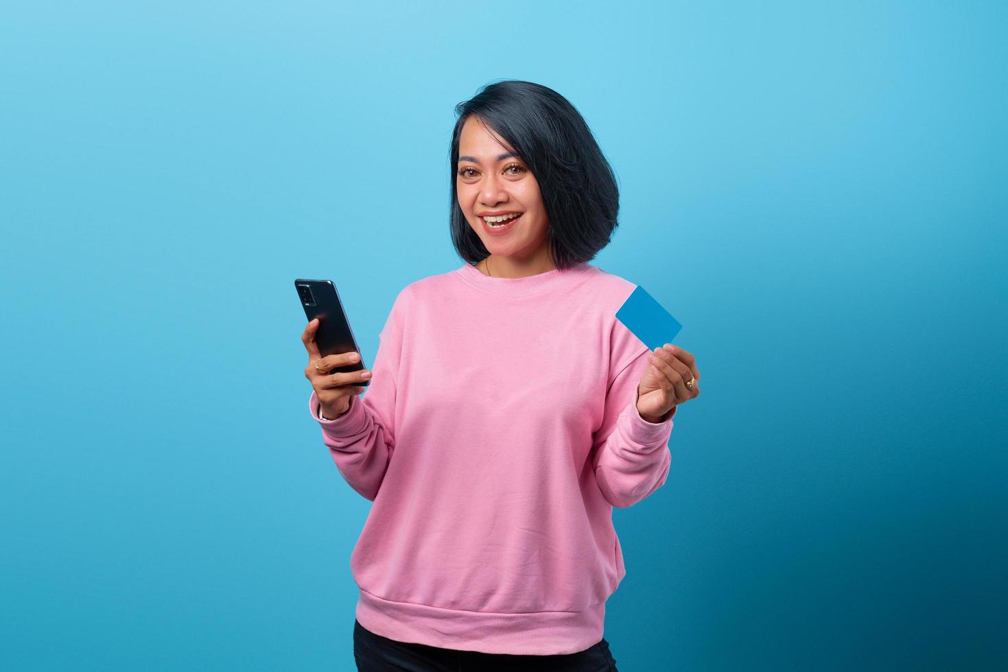 retrato de uma mulher bonita usando telefone celular e segurando um cartão de crédito foto