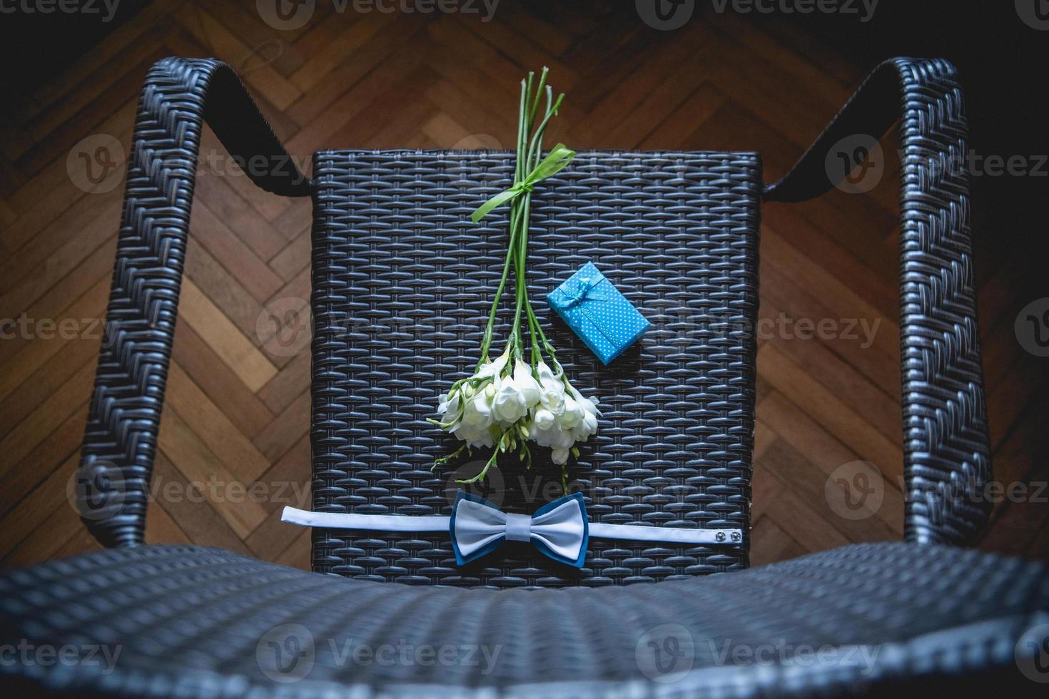 buquê de casamento, lenço borboleta e caixa de presente na cadeira. foto
