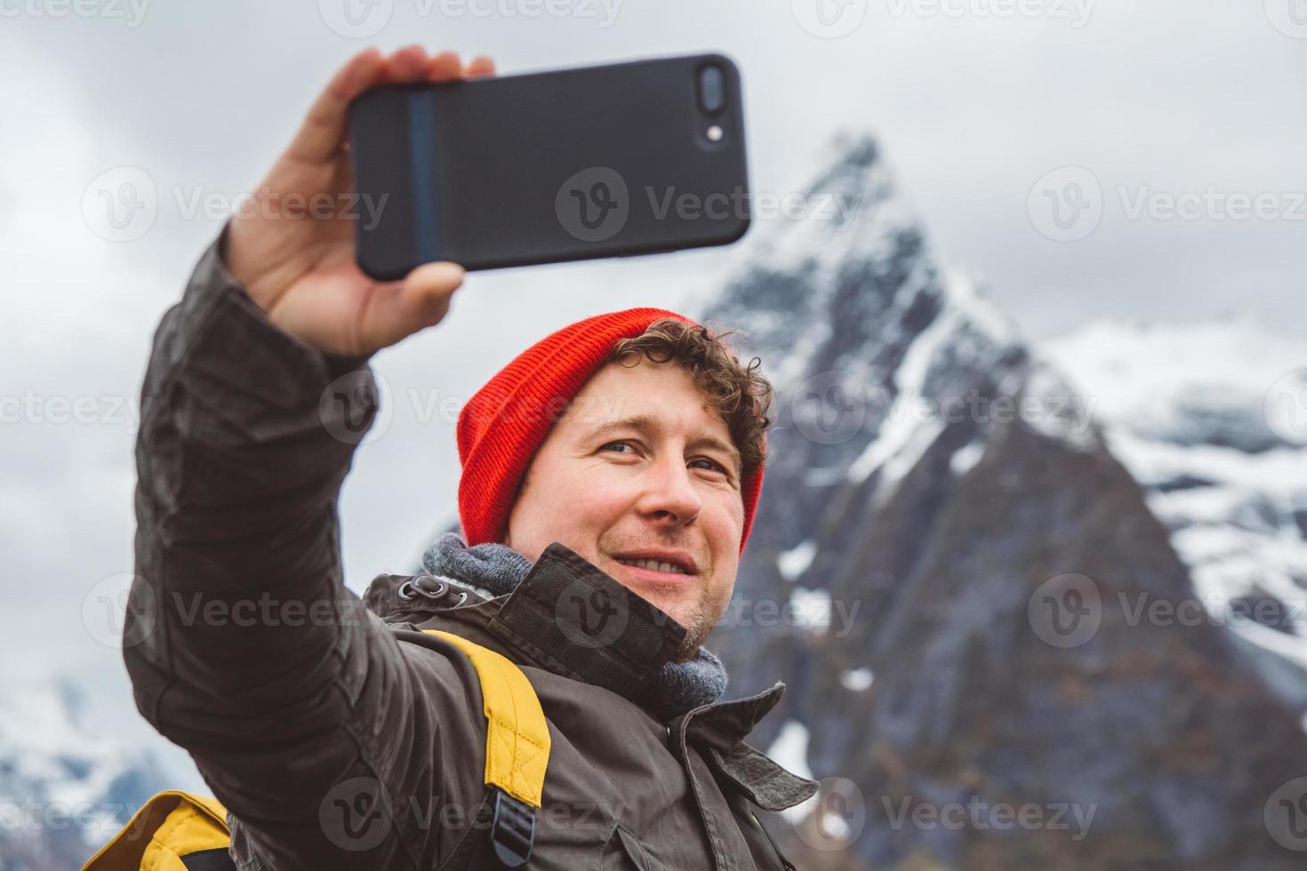homem tirando uma selfie com montanhas atrás dele foto