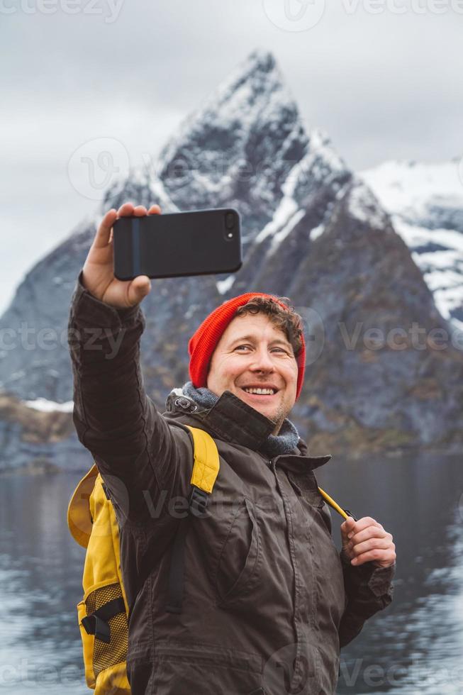 homem tirando uma selfie com montanhas atrás dele foto