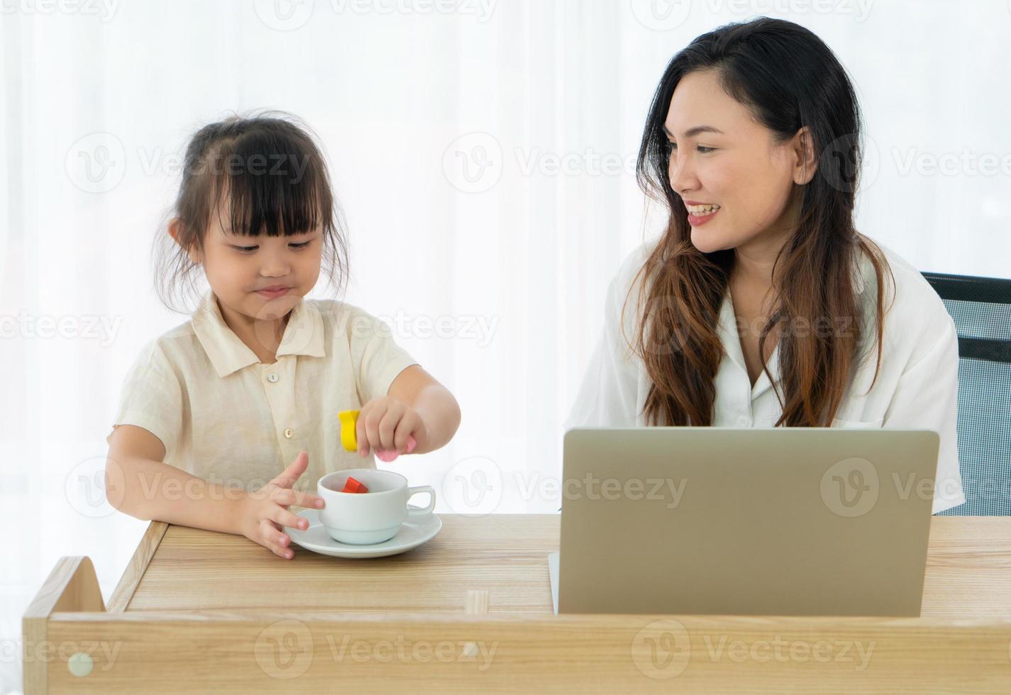 mãe e filha em uma mesa com um laptop foto