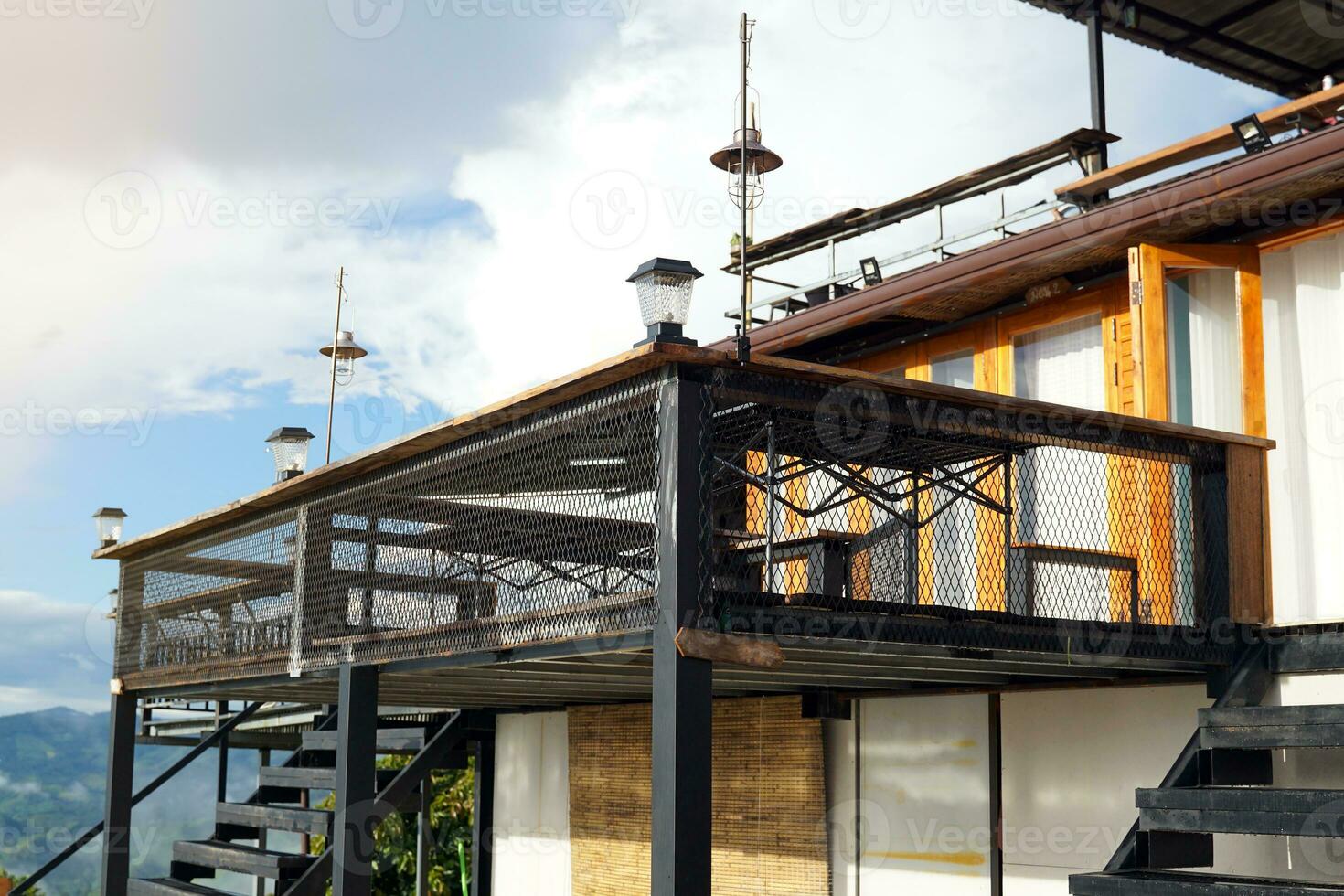 uma aço sacada estende a partir de a frente do a quarto para vendo a Alto montanha picos e névoa durante a chuvoso estação dentro norte tailândia. foto