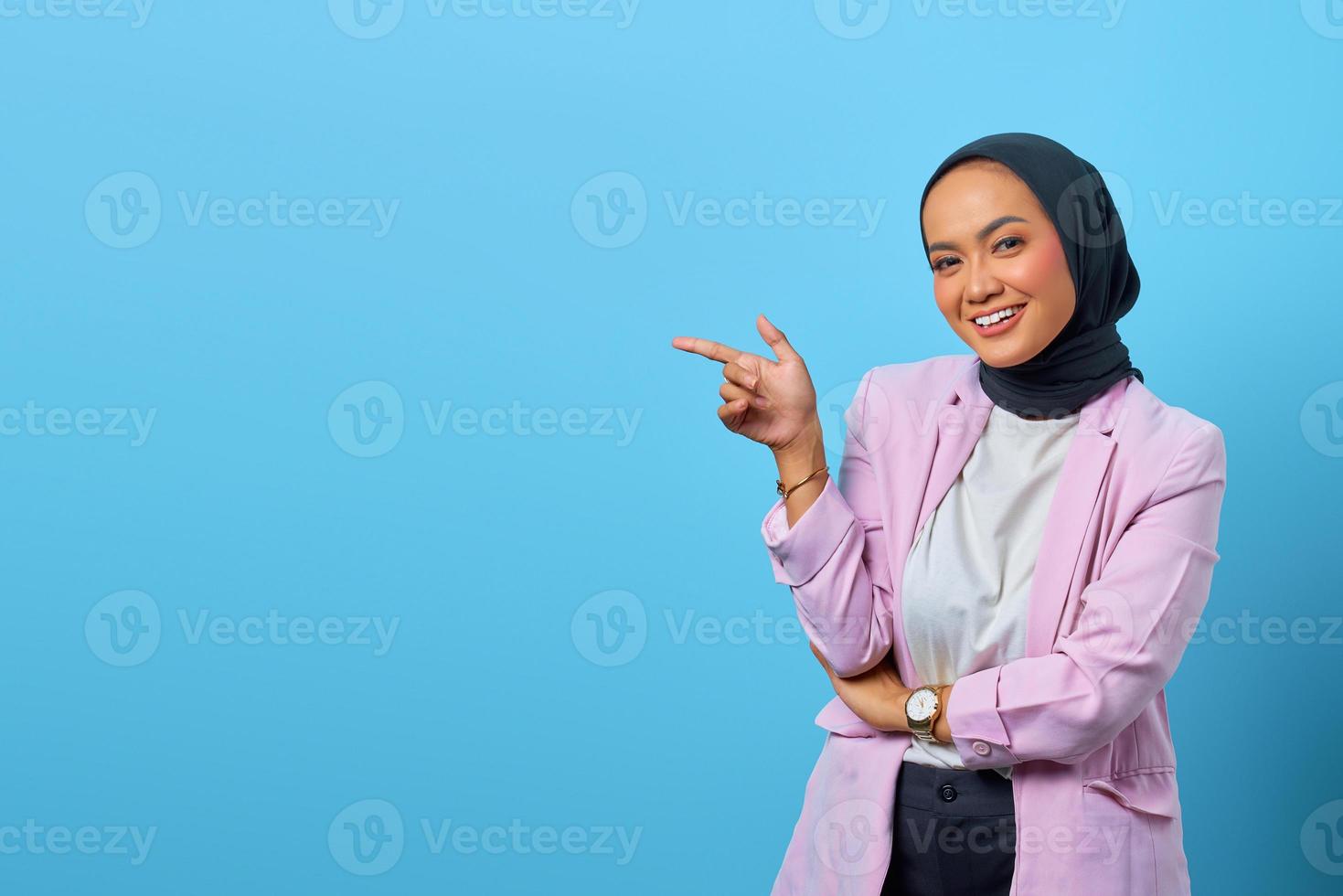 Mulher asiática alegre apontando o dedo para o espaço vazio foto
