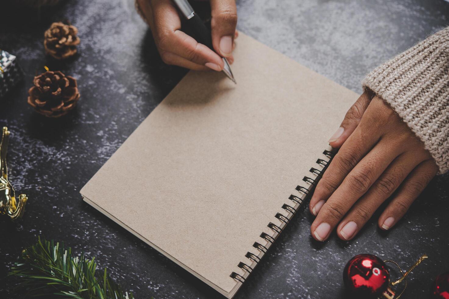 uma mão segurando uma caneta para escrever em um caderno com óculos foto