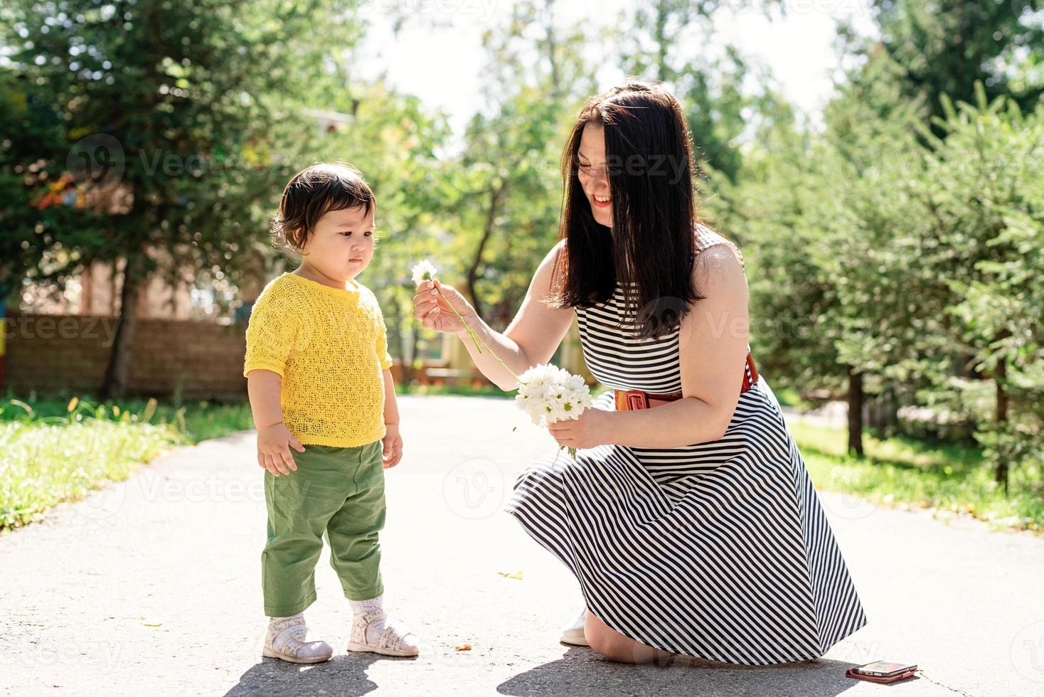 mãe passeando com a filha no parque dando flores para ela foto