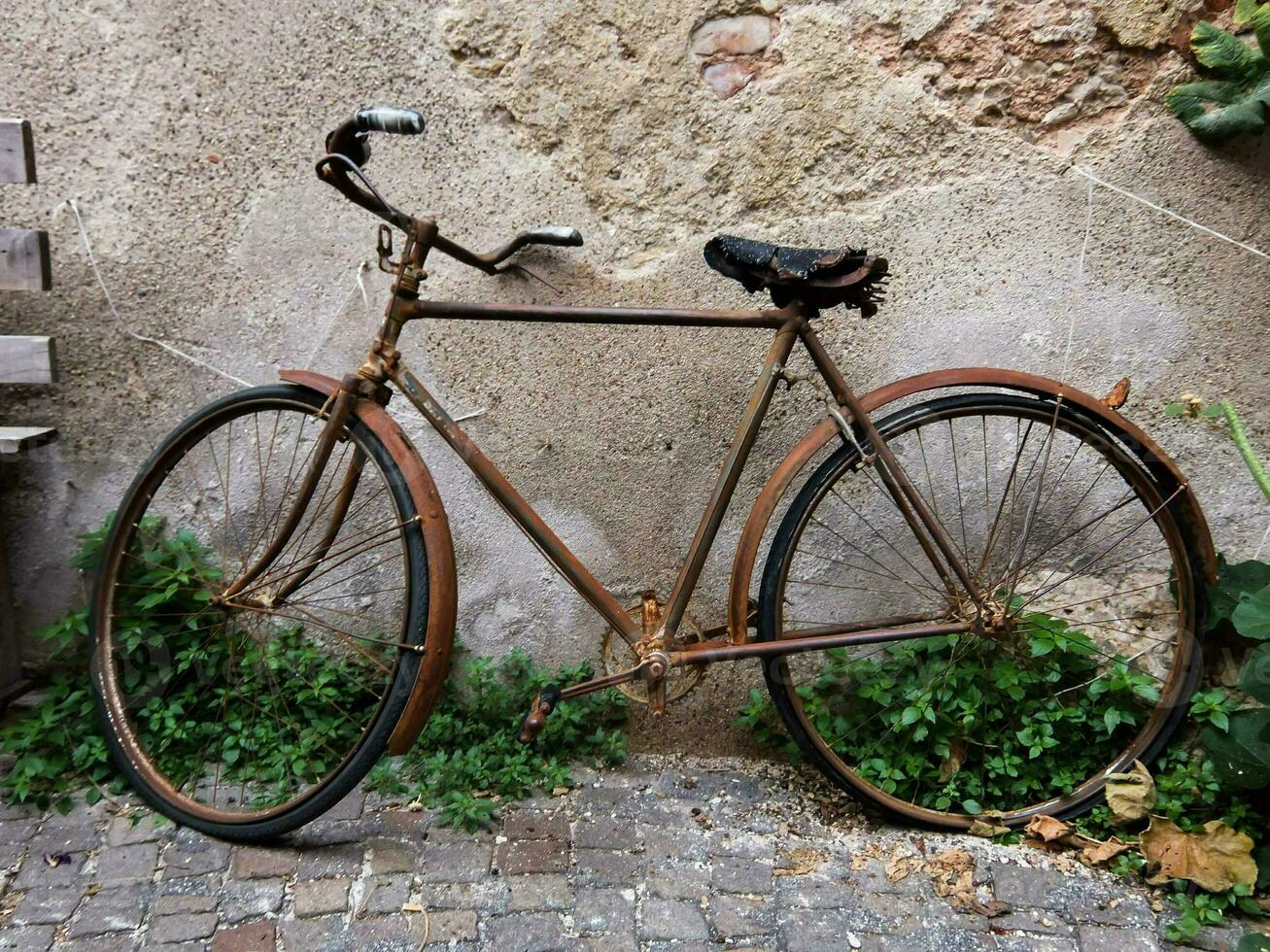 a velho oxidado bicicleta inclinado contra uma parede foto