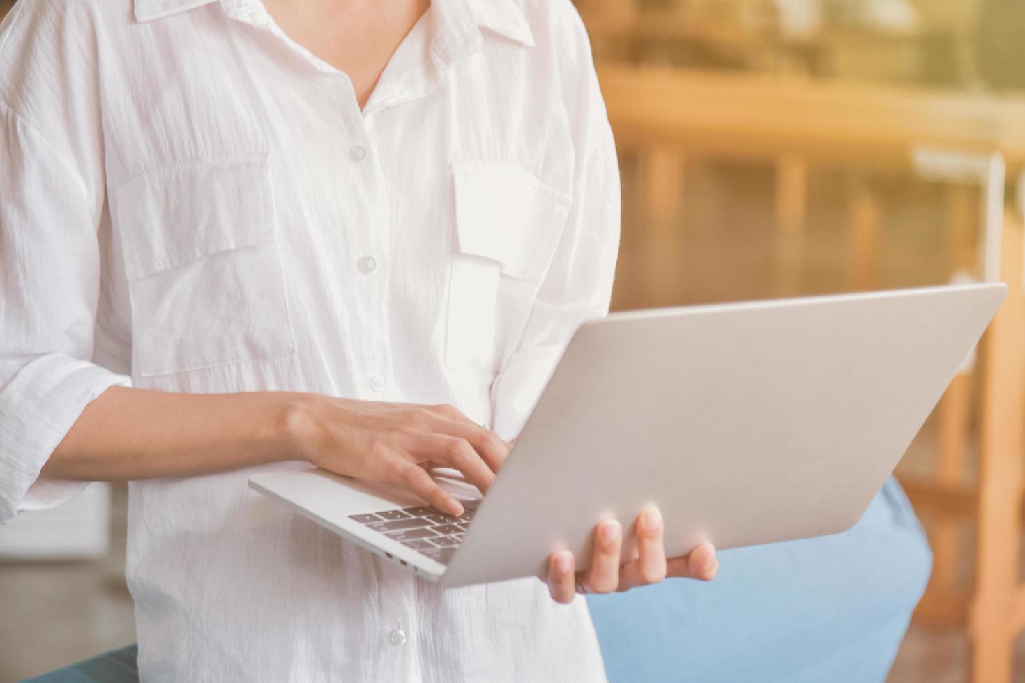 jovem usando e segurando um laptop prateado foto