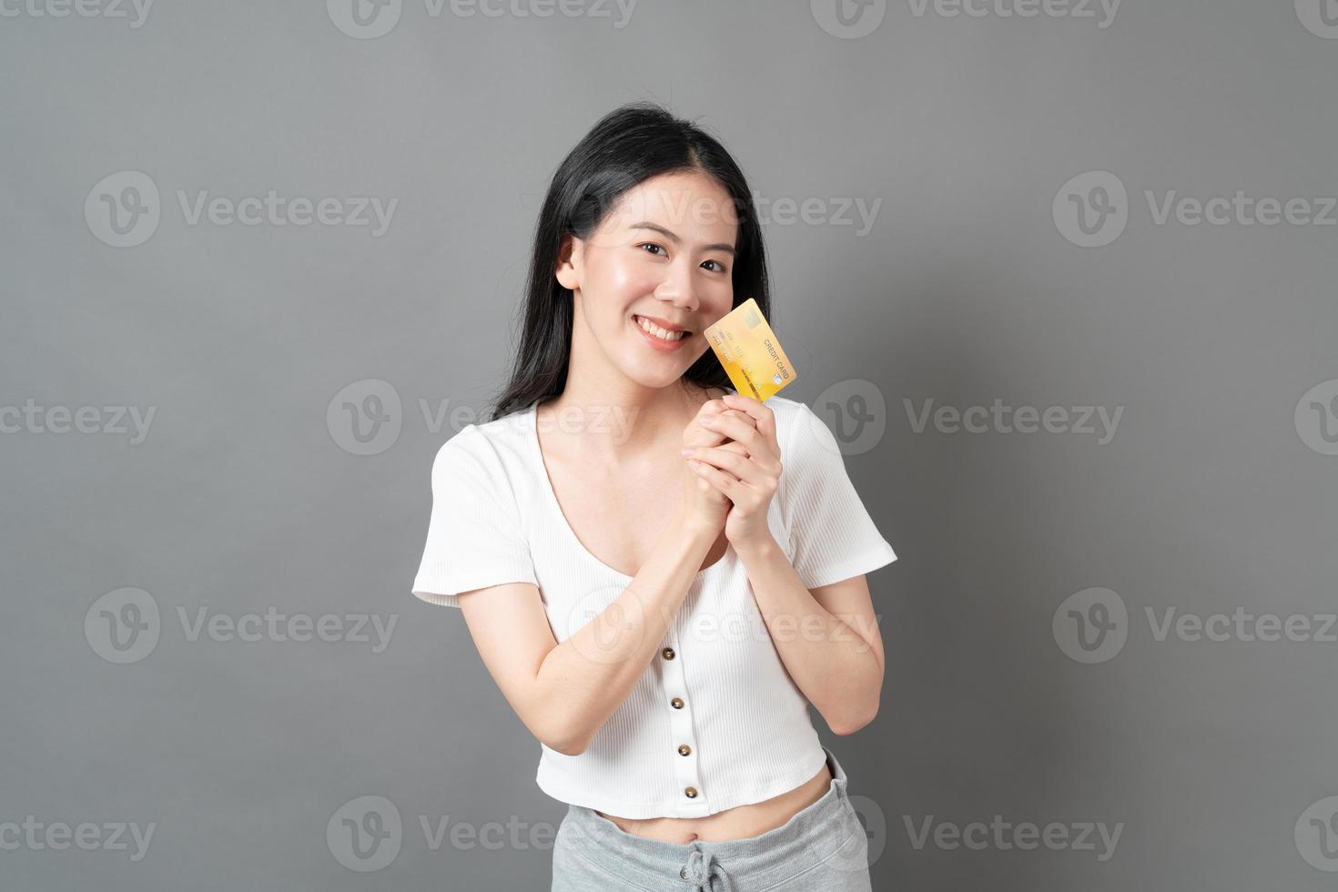 mulher asiática com cara feliz e apresentando cartão de crédito na mão foto