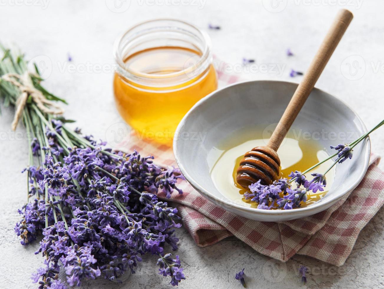 jarra com mel e flores frescas de lavanda foto