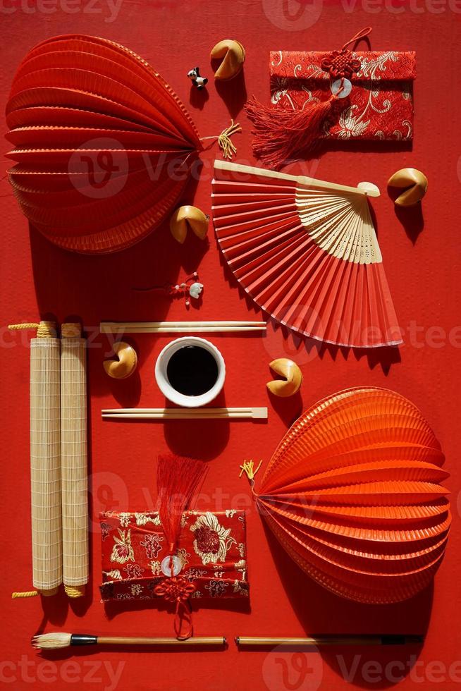postura plana de leques japoneses e objetos chineses decorativos em fundo vermelho foto