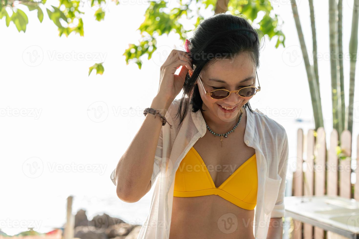 mulher feliz usando biquíni e óculos escuros para viajar na praia foto