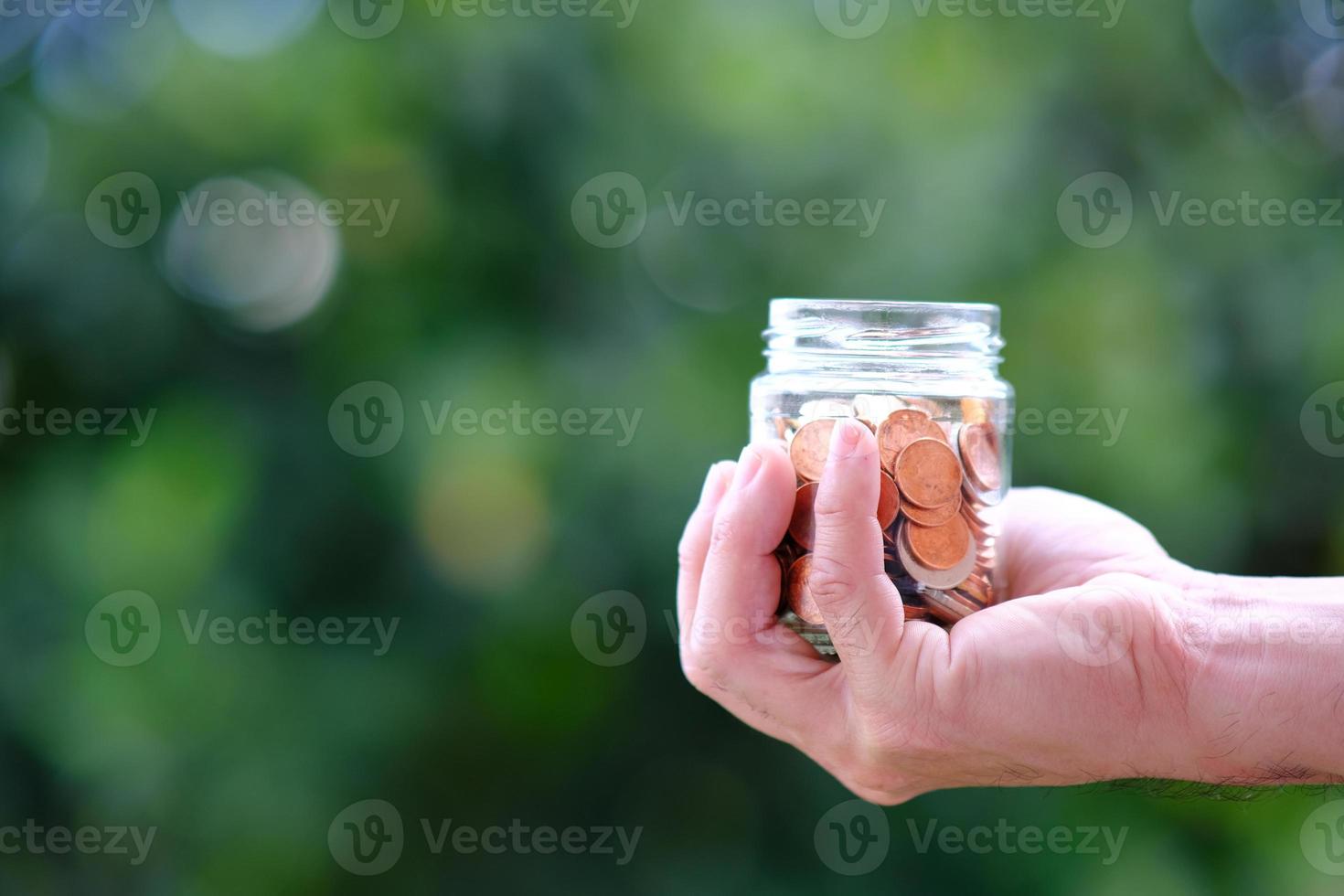 conceito de economia de dinheiro, mão segurando moeda no pote foto