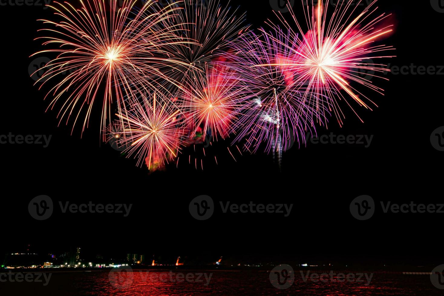 incríveis e lindos fogos de artifício coloridos na noite de celebração, mostrando na praia do mar com reflexo de várias cores na água foto