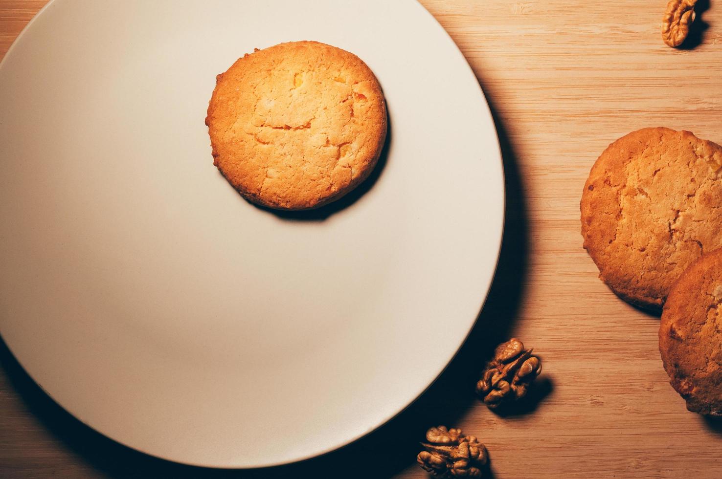 vista superior de biscoitos com nozes, em um prato branco e mesa de madeira foto