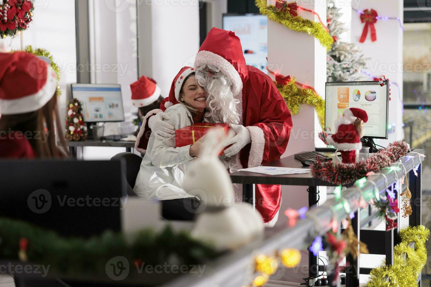 empregado disfarçado dentro santa claus abraçando colega de trabalho depois de oferta Natal presente durante inverno feriado temporada. trabalhador fazendo pensativo gesto para colega, dando apresenta dentro festivo adornar escritório foto