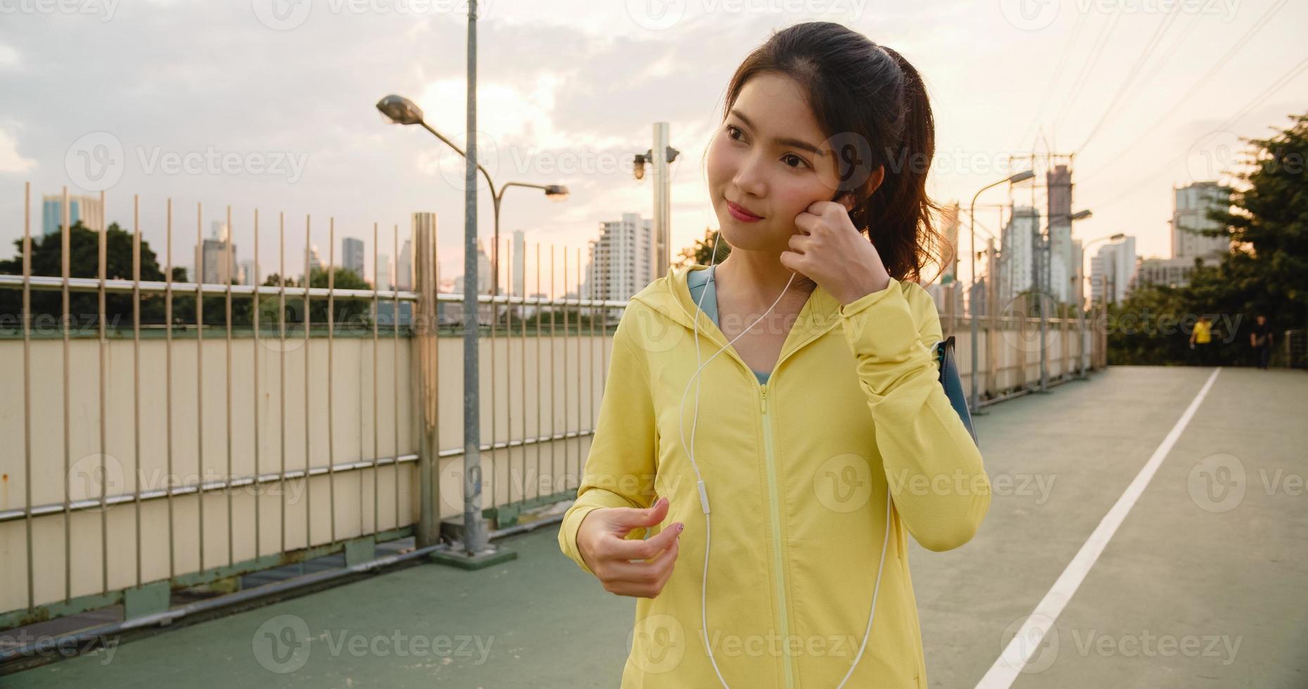 Ásia atleta senhora exercícios usando smartphone para ouvir música. foto