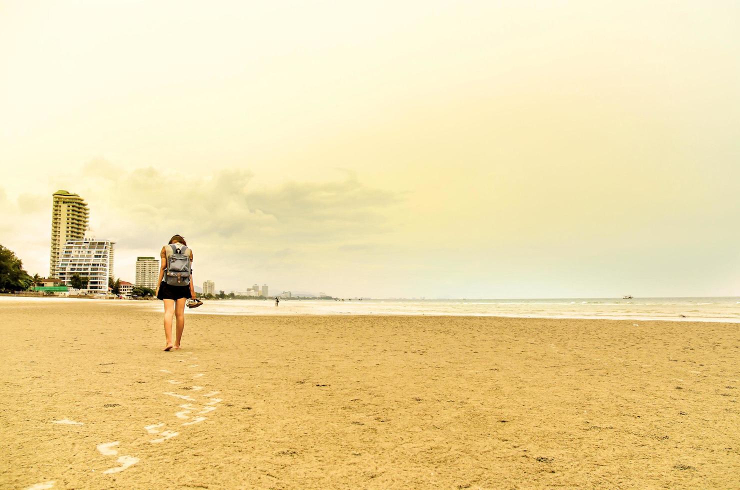 o viajante fica na areia da praia e olha as pessoas estão nadando foto