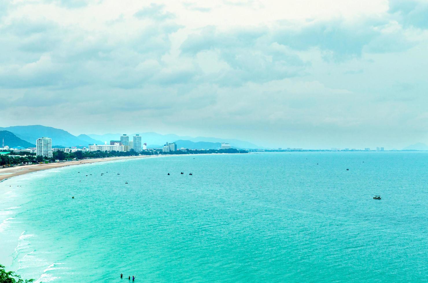 a vista da praia de areia e ondas do mar com rocha e recife na manhã foto