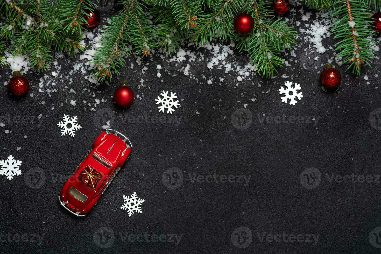 Natal ou Novo ano decoração fundo modelo miniatura vermelho carro. para abeto árvore galhos em Preto fundo com cópia de espaço. plano deitar. padronizar. branco flocos de neve e neve, vermelho bolas foto