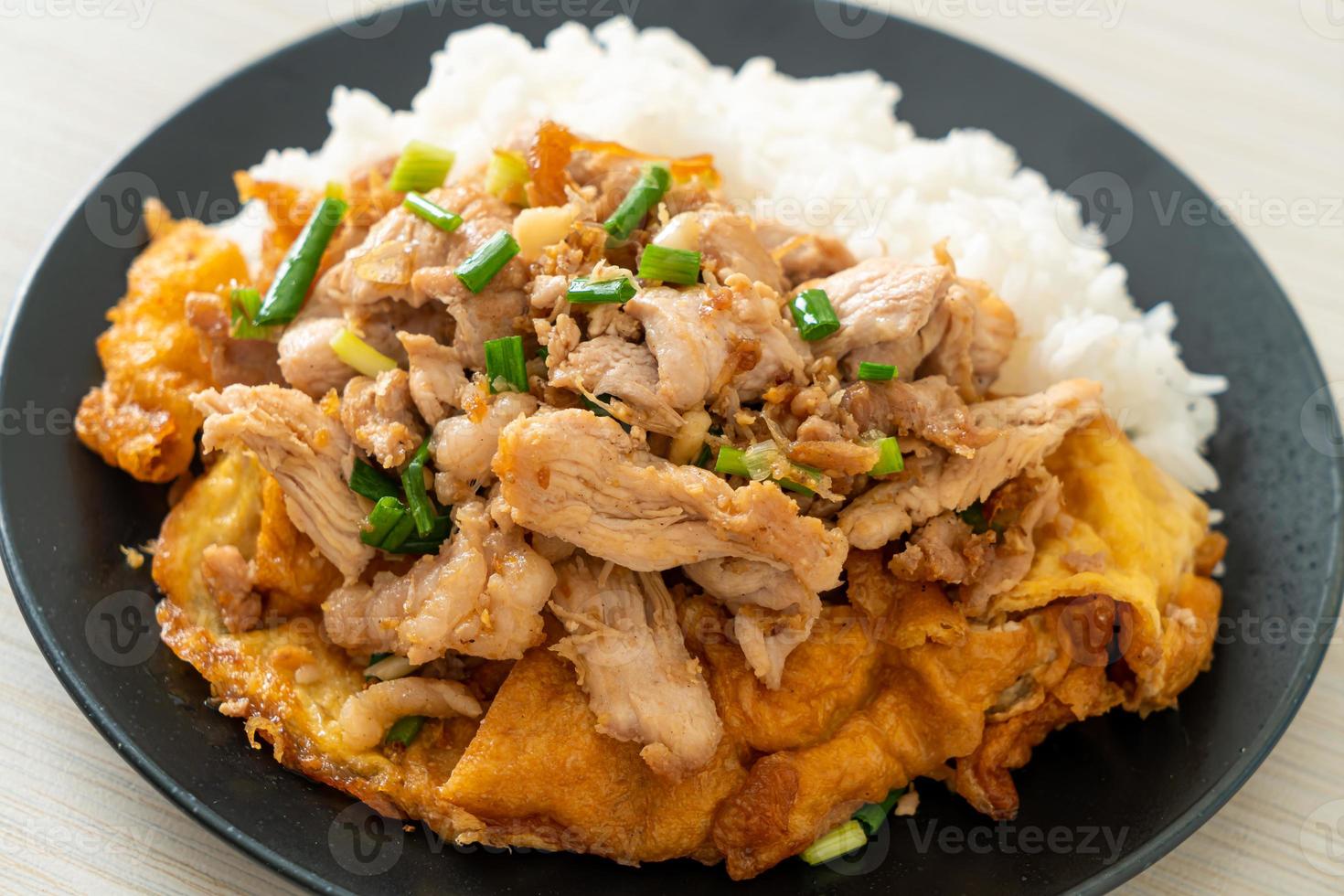 Carne de porco frita com alho e ovo coberto com arroz foto