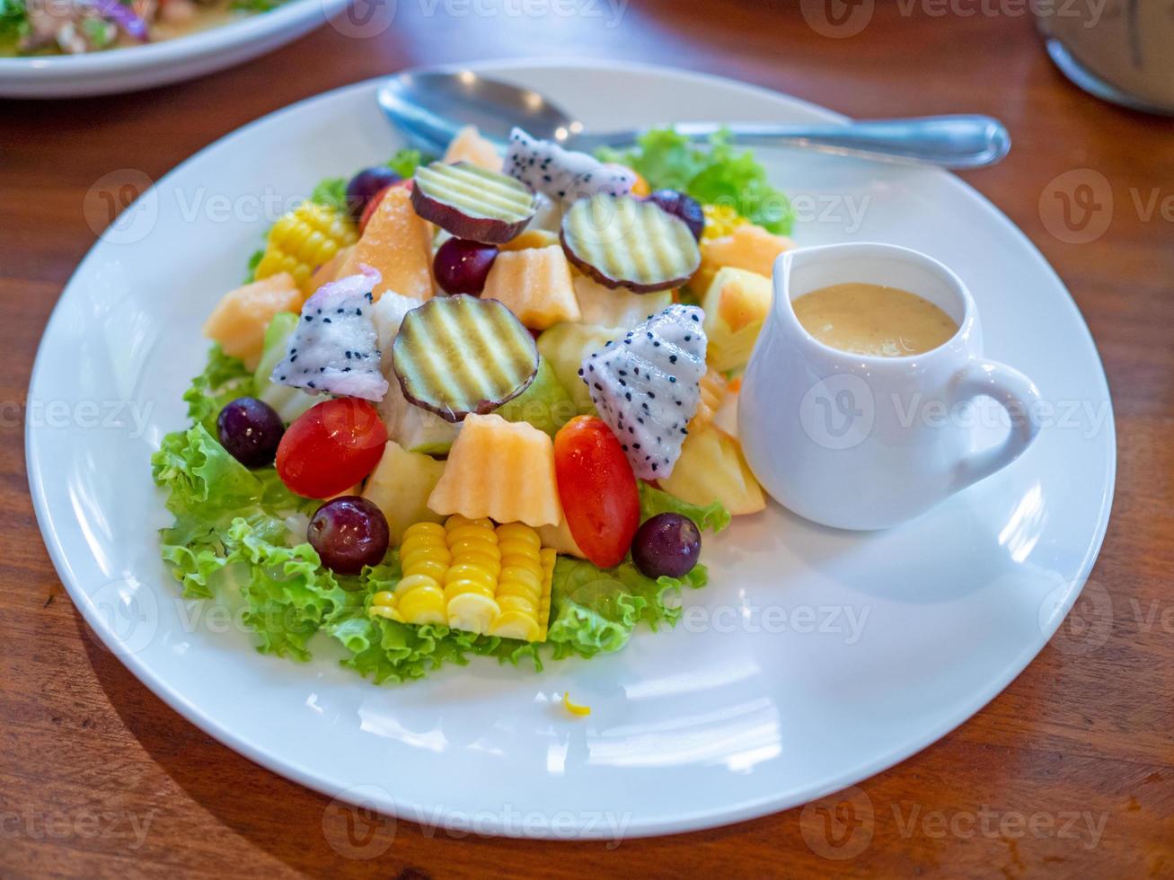 salada de legumes em um prato branco colocado sobre um fundo de madeira. foto