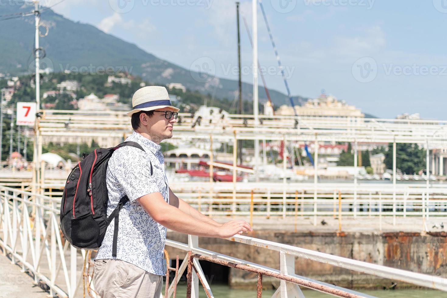 turista caminhando no porto marítimo, barcos e iates ao fundo foto