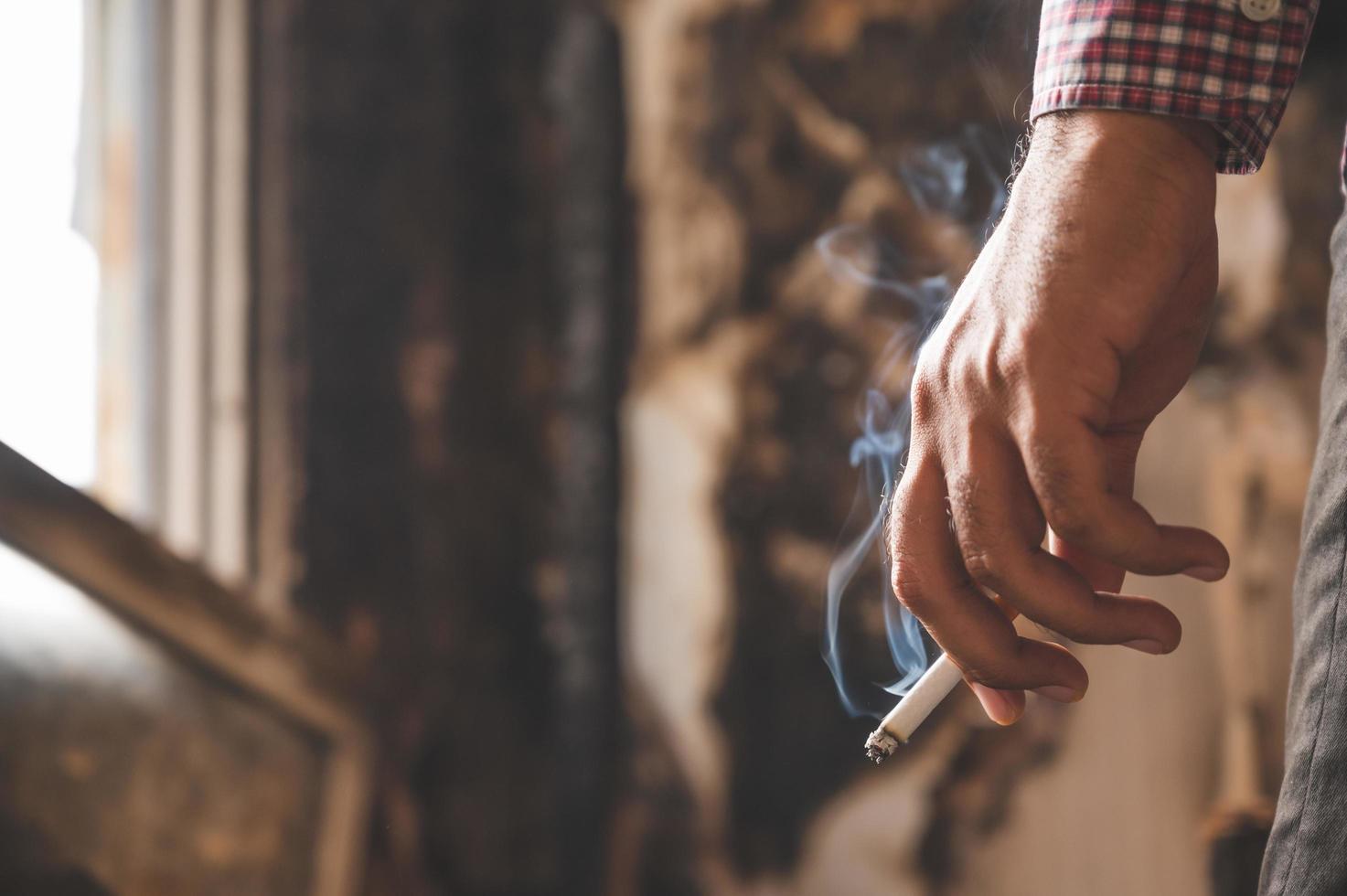 feche a mão masculina segurando um cigarro. foto