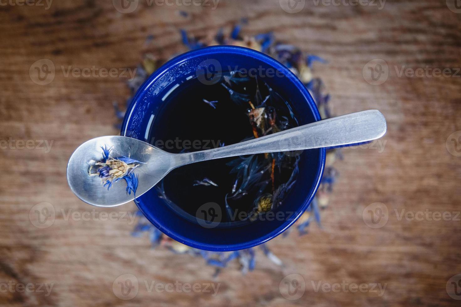 xícara e colher azuis com chá preto florido em um fundo de madeira foto