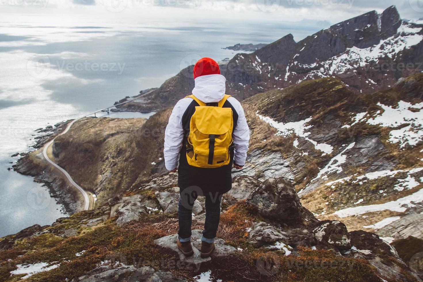 homem com uma mochila de pé no fundo das montanhas e do mar foto