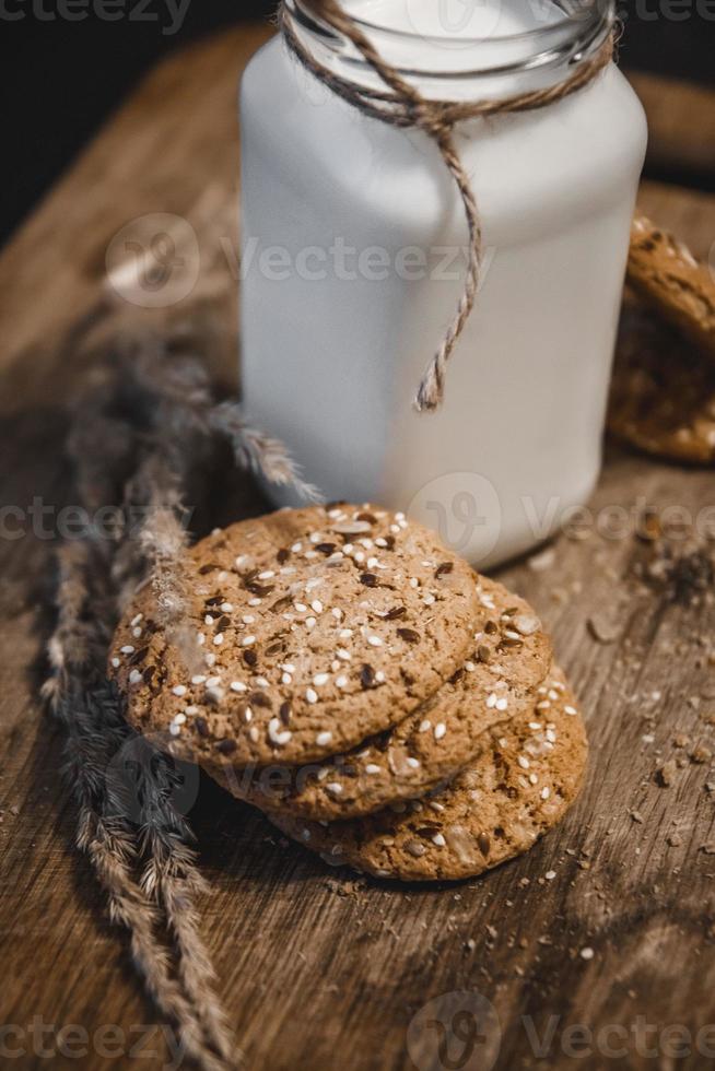 biscoitos de cereais com uma jarra de leite em um fundo de madeira. foto