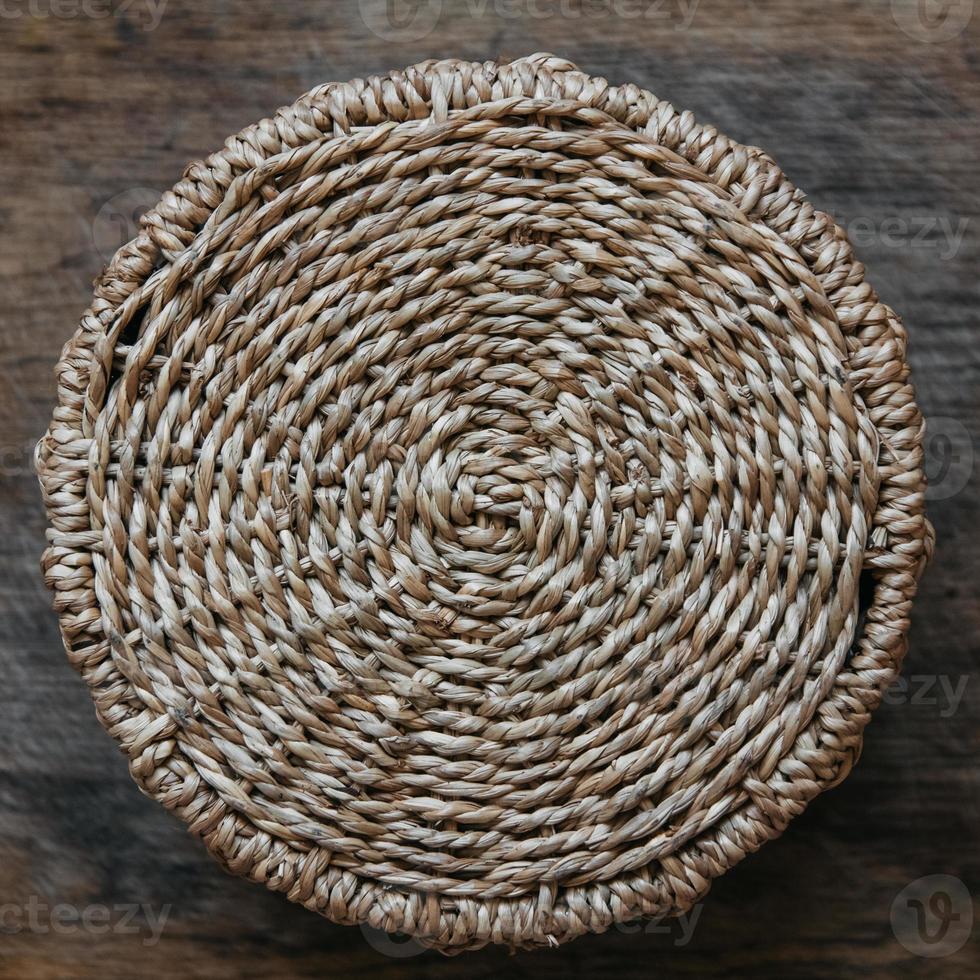 elemento de uma cesta de vime redonda em um fundo de madeira foto