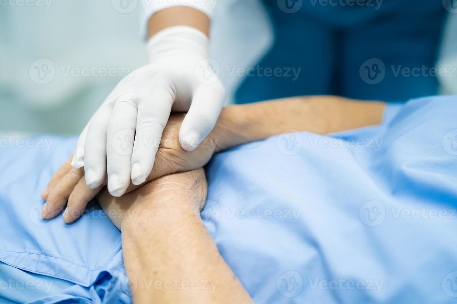 médico segurando mãos comoventes paciente asiática sênior com amor foto