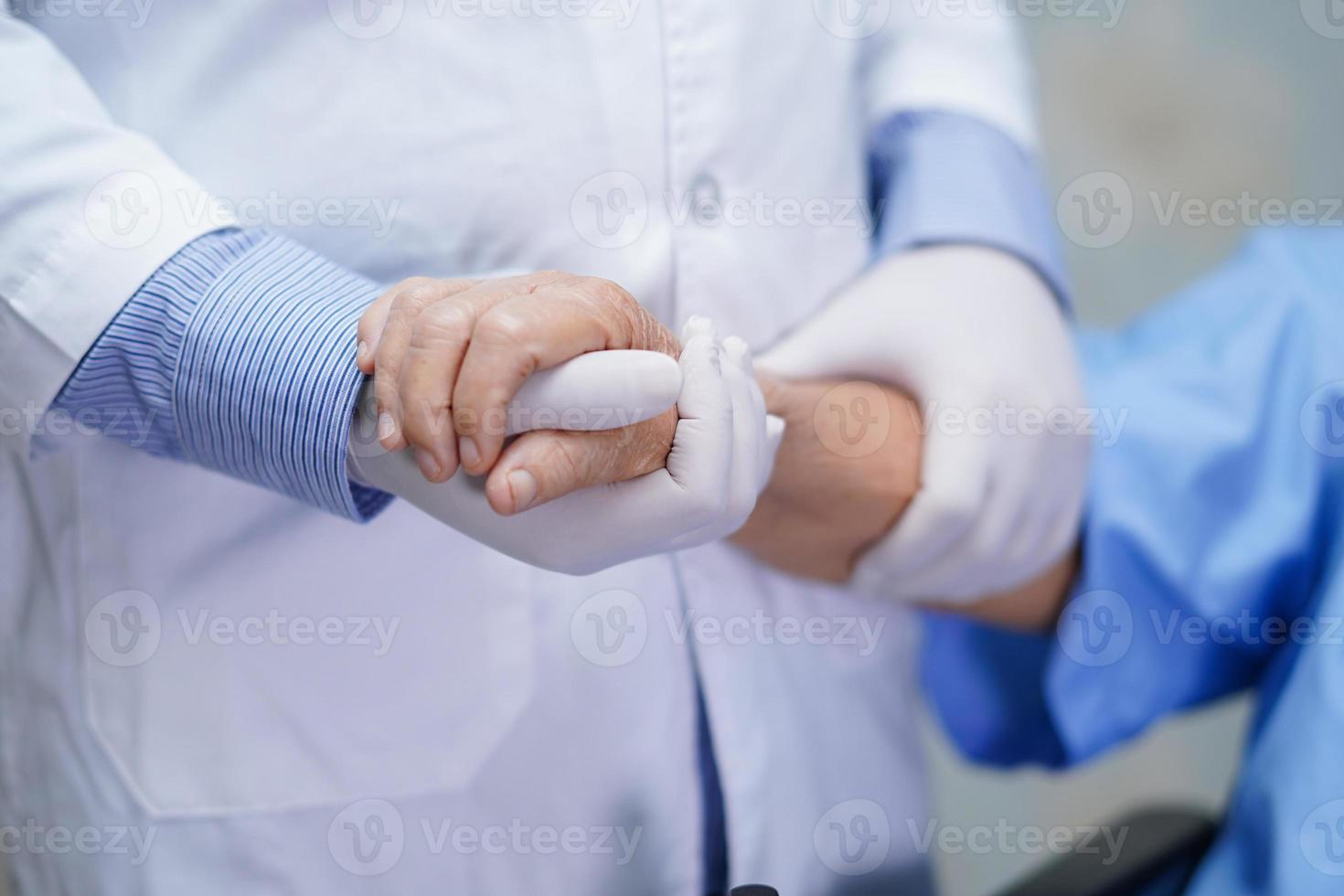 médico segurando mãos comoventes paciente asiática sênior com amor foto