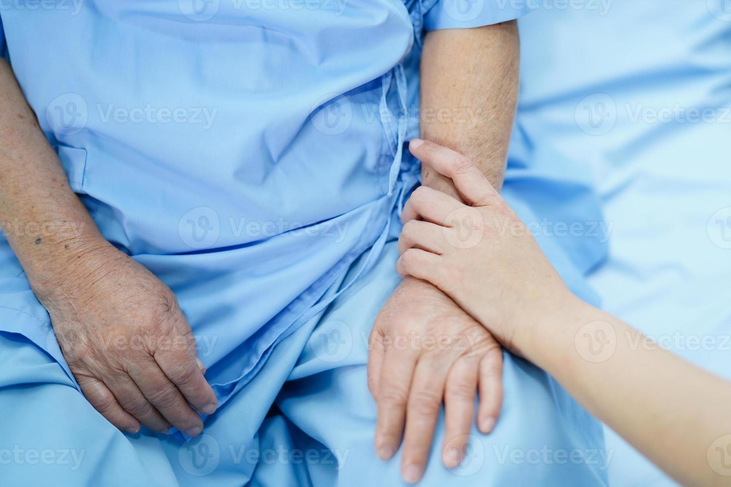 tocando as mãos paciente sênior asiática com amor foto