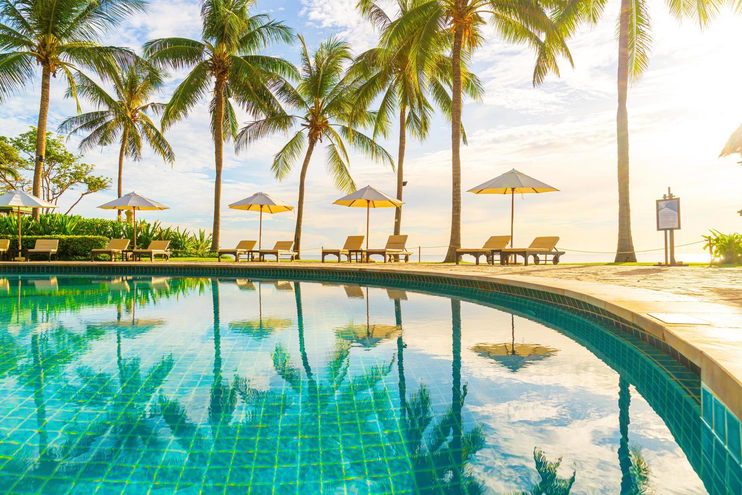 lindo guarda-sol de luxo e cadeira ao redor da piscina ao ar livre foto