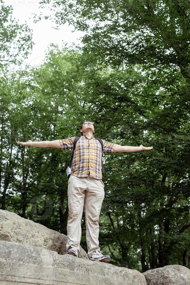 jovem de pé em uma grande pedra na floresta, olhando para longe foto