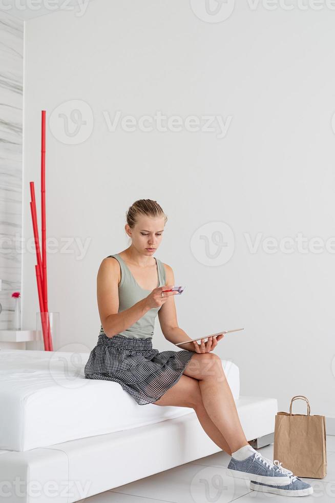 jovem fazendo compras online sentada em casa na cama foto