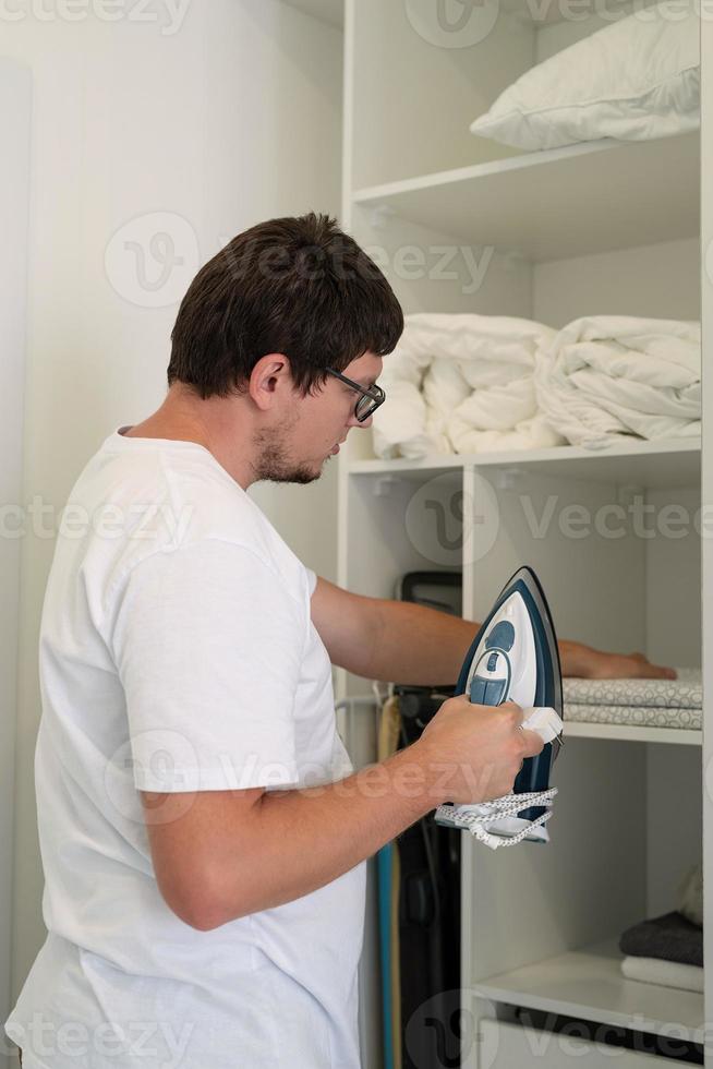 jovem passando roupa em casa foto