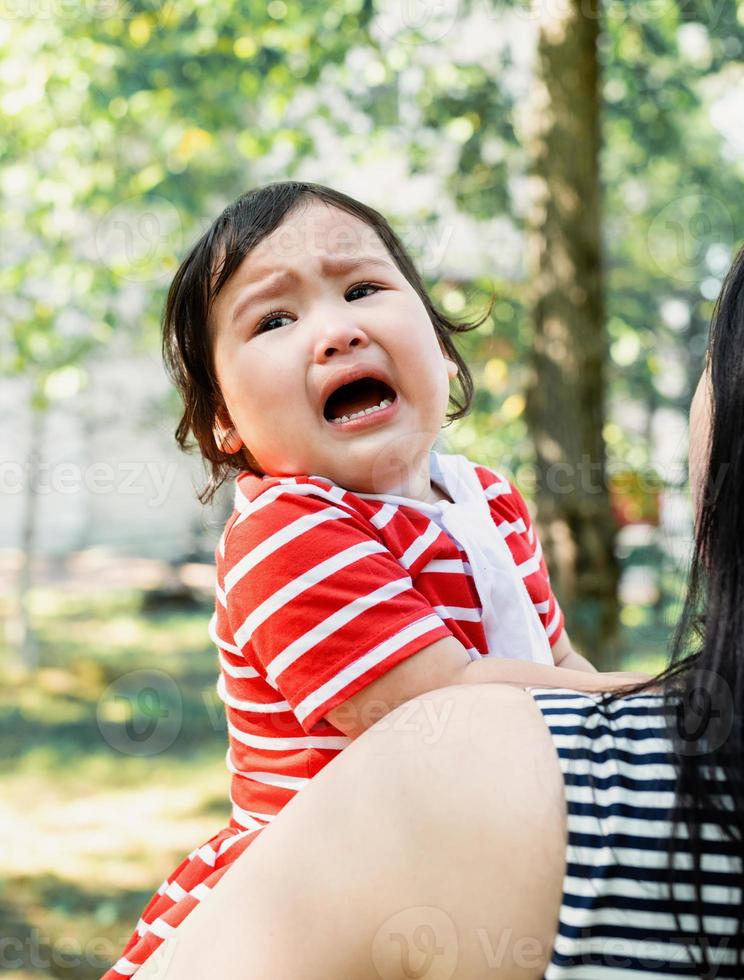 menina asiática chorando nas mãos da mãe foto