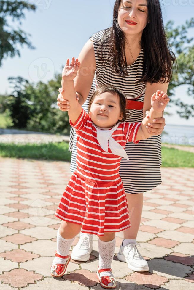 família multirracial feliz de mãe e filha caminhando no parque foto