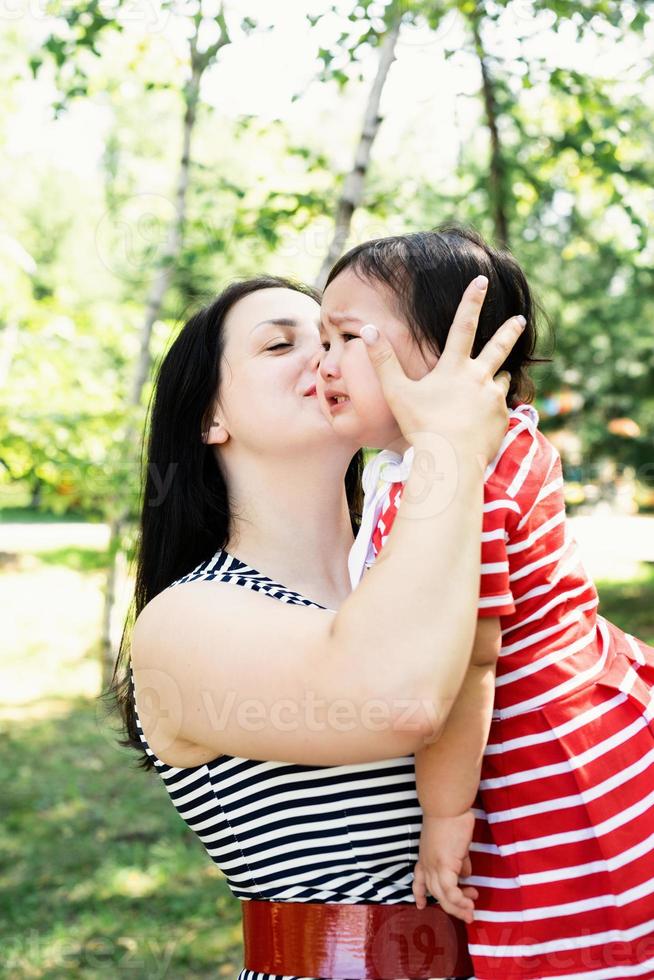mãe beijando e acalmando sua filha bebê foto