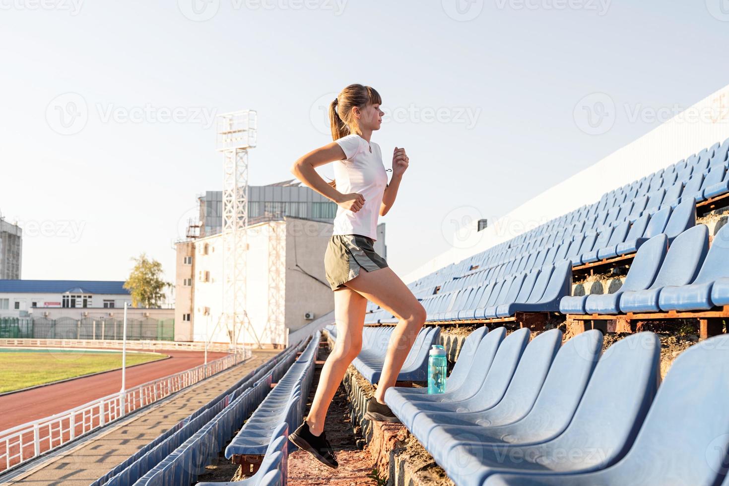 adolescente malhando no estádio subindo as escadas correndo foto