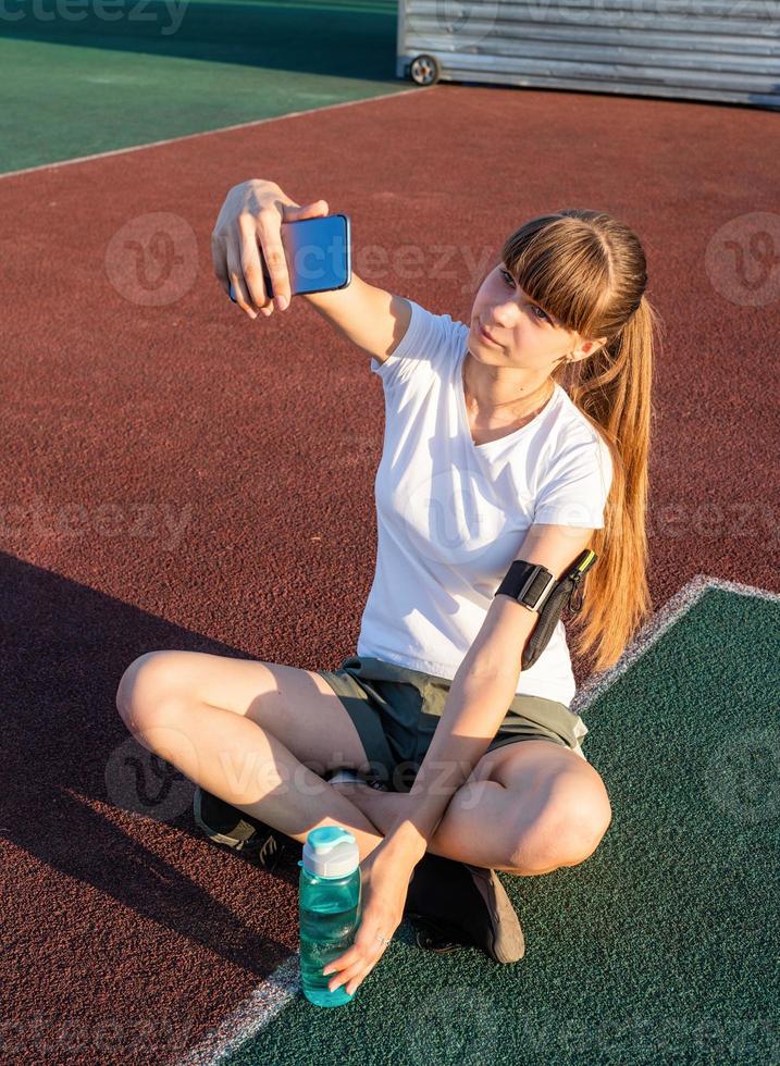 menina adolescente fazendo selfie no estádio depois do treino foto