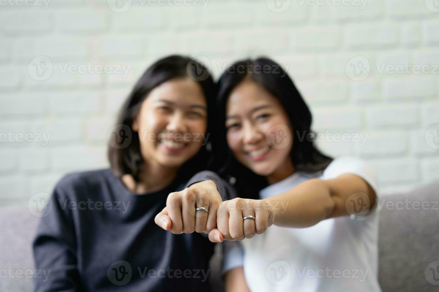 jovem ásia casal é feliz para mostrar fora seus argolas às lar. feliz jovem ásia lésbica casal abraçando cada de outros dentro a vivo quarto às lar. foto